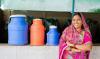 A female farmer of India is grinning with milk container at her back