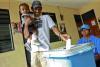 A father with his child in his arm is casting his vote ballot in Timor-Leste. 